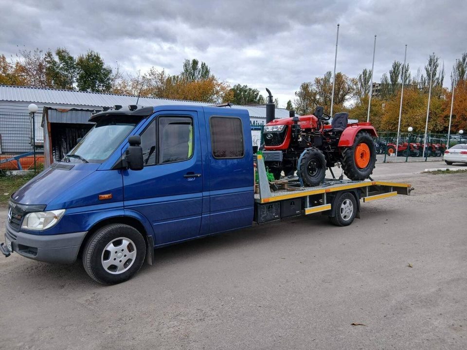 Синий эвакуатор перевозит трактор